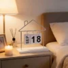 Lịch decor số để bàn với khung kim loại hình ngôi nhà và thẻ lịch lật thay đổi ngày tháng. Thiết kế tối giản, hiện đại, phù hợp trang trí bàn làm việc, bàn học, kệ sách hoặc không gian quán cà phê.